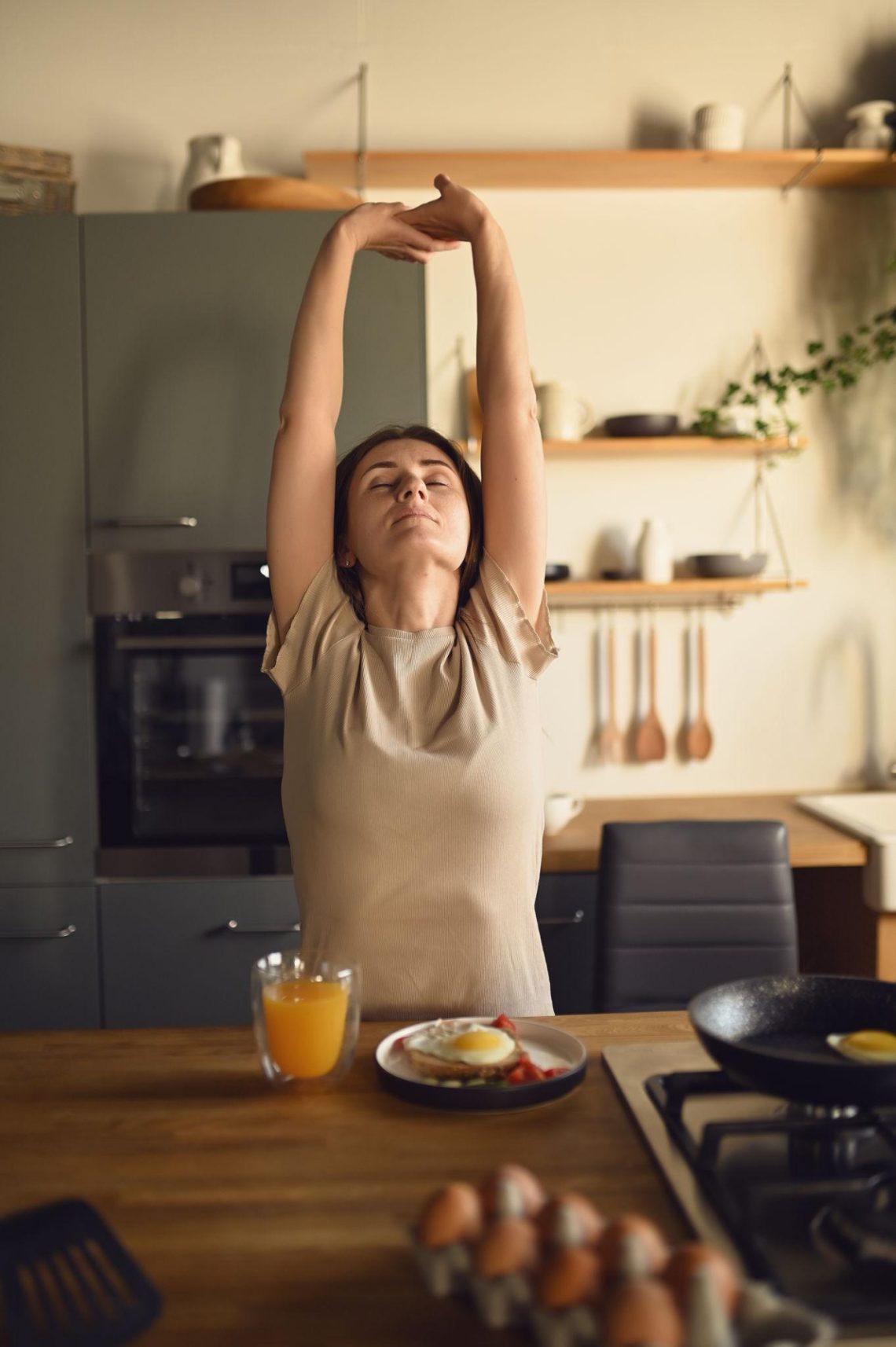 Woman practicing a healthy morning wellness routine with stretching, water, and a balanced breakfast at home.