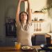 Woman practicing a healthy morning wellness routine with stretching, water, and a balanced breakfast at home.