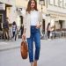 Woman wearing a timeless minimalist outfit with a white shirt, beige blazer, and classic blue jeans.